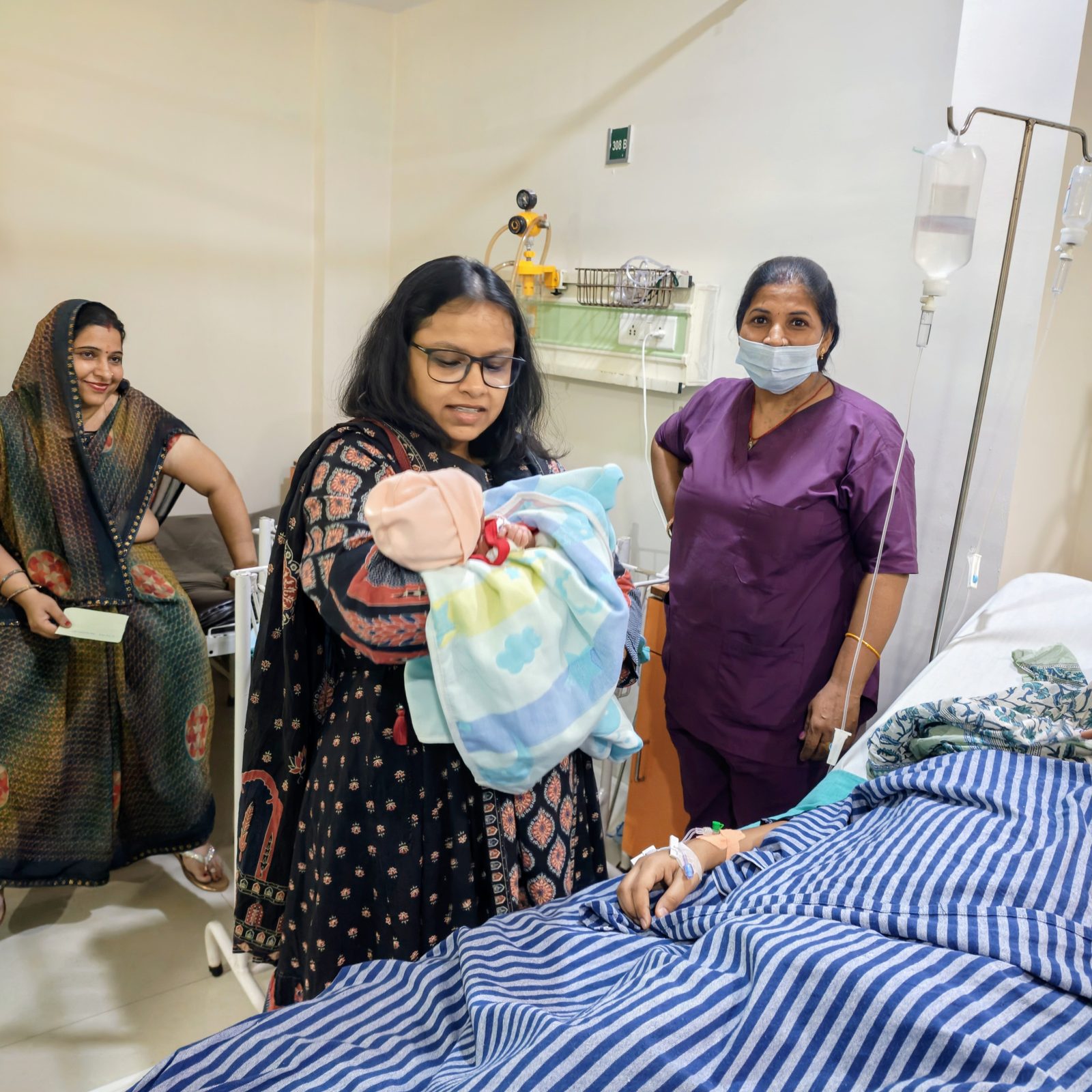 Dr. Anam Ghani showing newborn to family at bedside